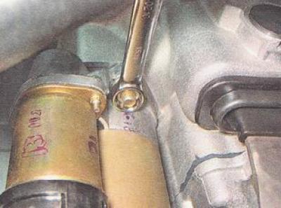 6. Using a 15 mm open-end wrench or a socket wrench with an extension, unscrew the two starter…