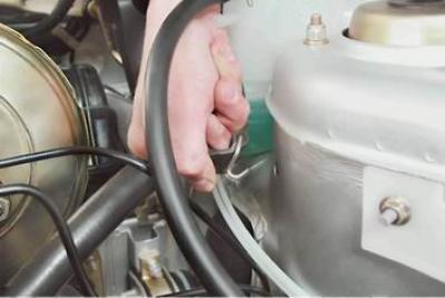 8. Отсоединяем резиновый ремень крепления расширительного бачка системы охлаждения и отводим бачок…