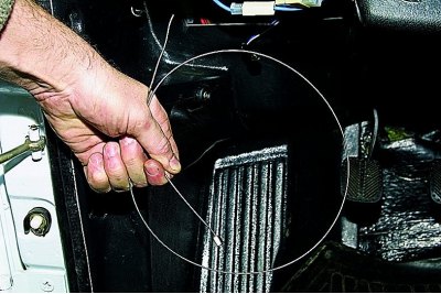 През отвора в дръжката за заключване на капака (арматурното табло е премахнато за по-голяма яснота)…